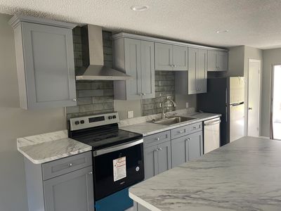 Modern kitchen with gray Shaker cabinets and Calcutta marble countertops. Install in Spring hill