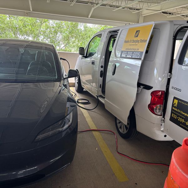 Tesla EV Electric car mobile charging service in parking lot.