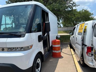 Mobile EV electric car charging of a BMW i3 in a parking lot by a mobile V charging truck