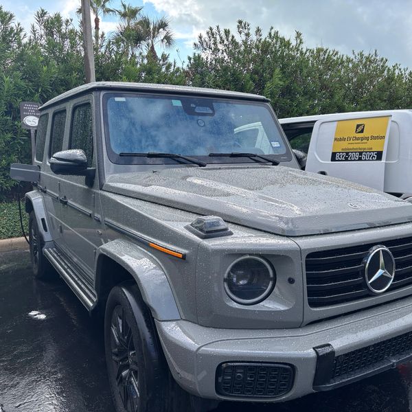 Electric vehicle mobile charging white van servicing a grey Mercedes G580 "G-wagon" in Galveston.