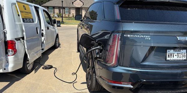 Electric Cadillac Escalade IQ being charged by a white van Mobile EV Fast Charger.