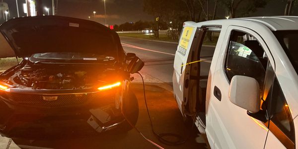Electric Cadillac OPTIQ being charged by a white van Mobile EV Fast Charger giving roadside EV charg