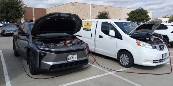 Electric car and van parked with hoods open for charging or jump-starting.