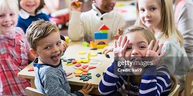 Happy children playing with colorful blocks at a classroom table.
