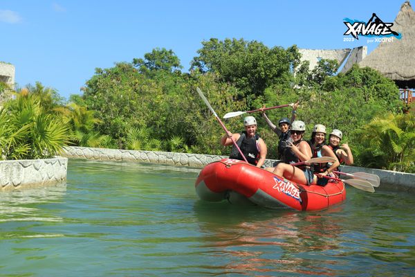 Group of friends rafting in a red boat on calm water, smiling and having fun.