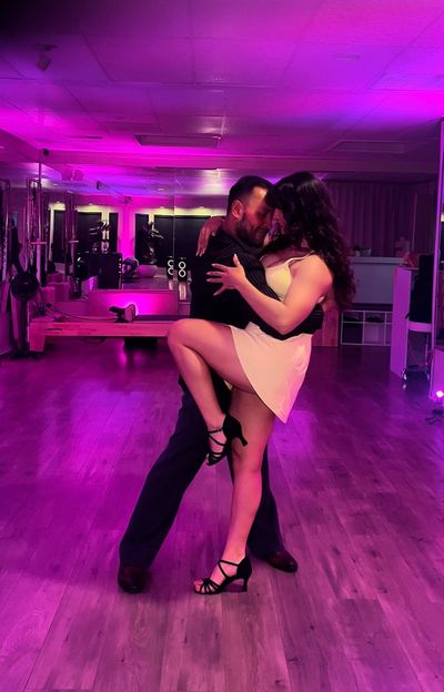Couple dancing passionately in a purple-lit room.