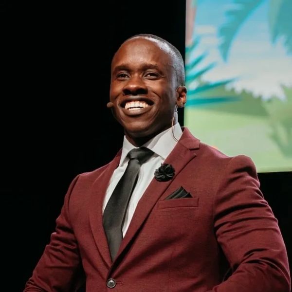 Confident man in maroon suit smiling during a presentation.