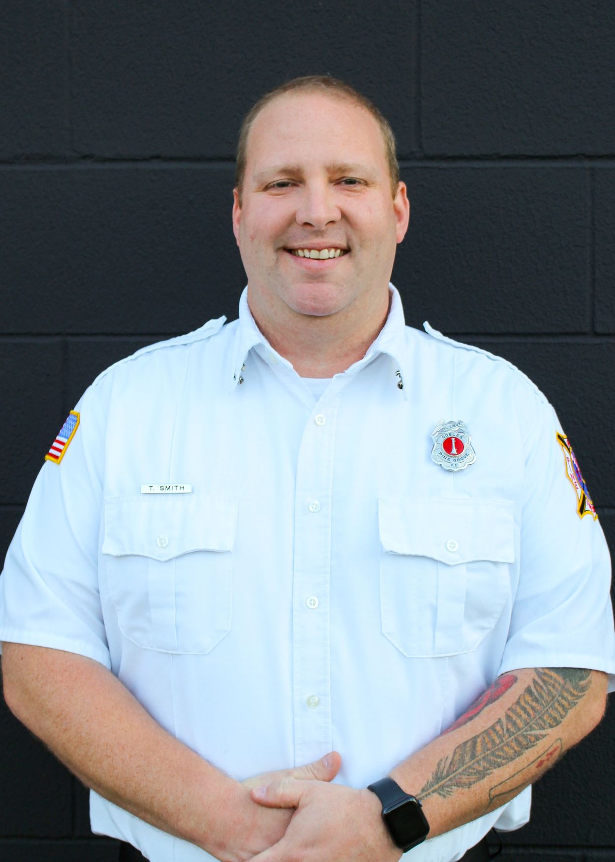 Man in white uniform with a smile and tattoo on arm.