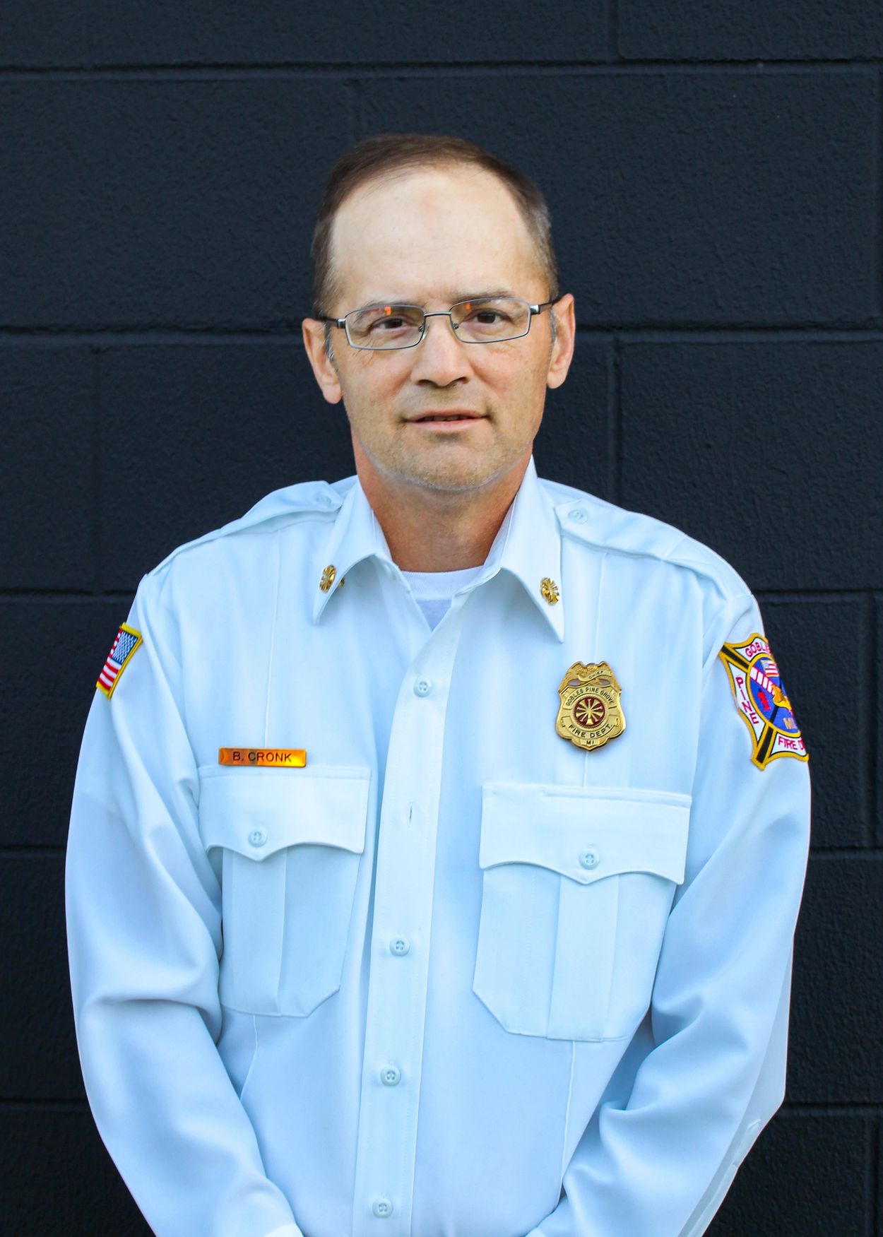 Firefighter in uniform posing against a dark background.