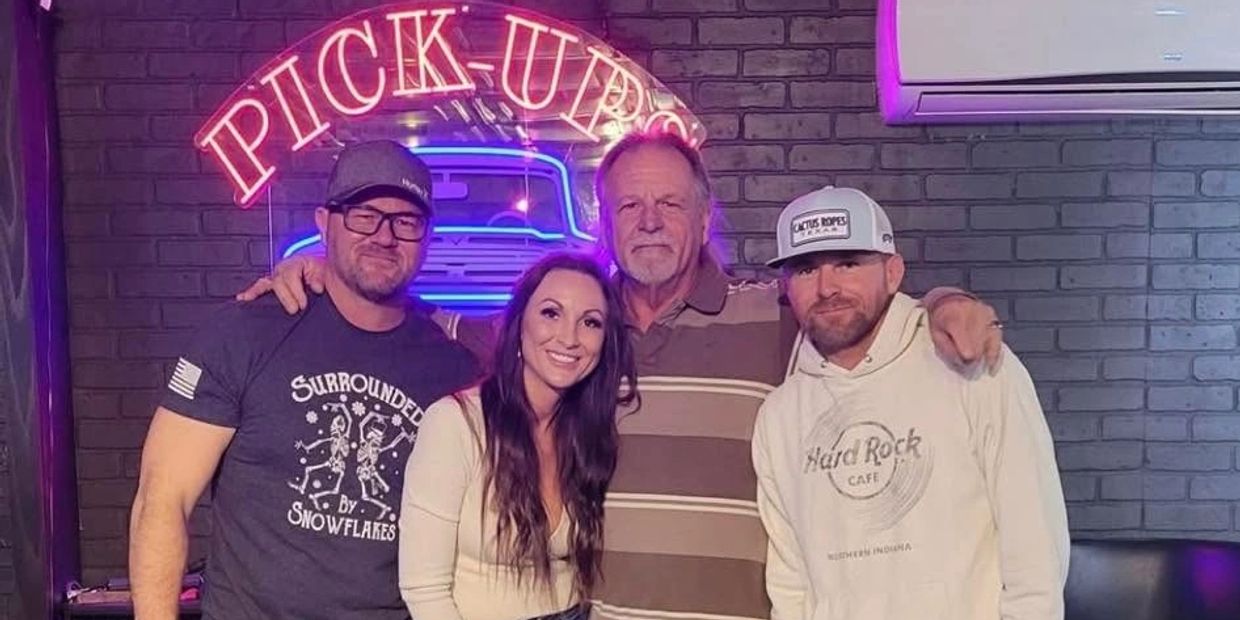 Four adults smiling under a neon sign that says PICK-UP.