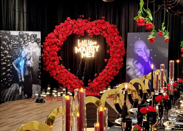 Romantic marriage proposal setup with red roses and candles.