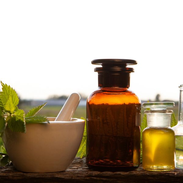 Herbal medicine setup with mortar, pestle, and bottles in natural light.