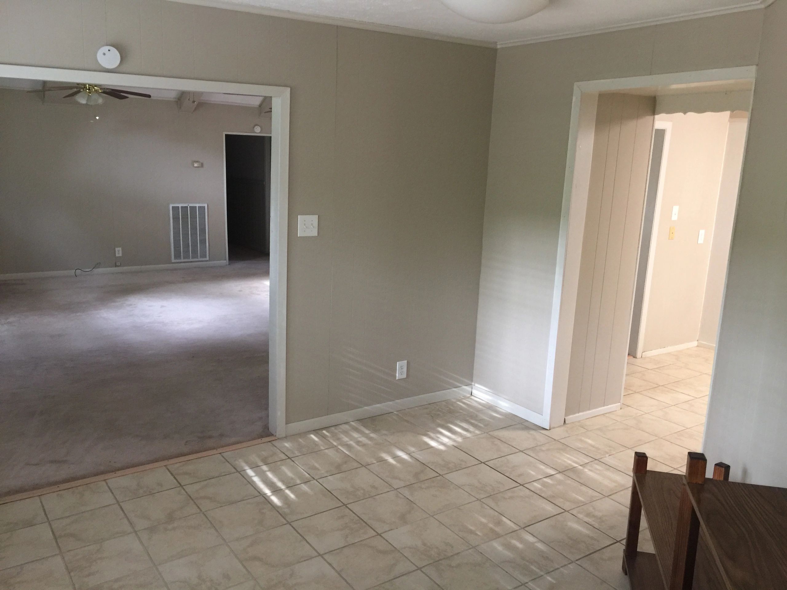 Empty rooms with beige walls and tiled floors in a house.