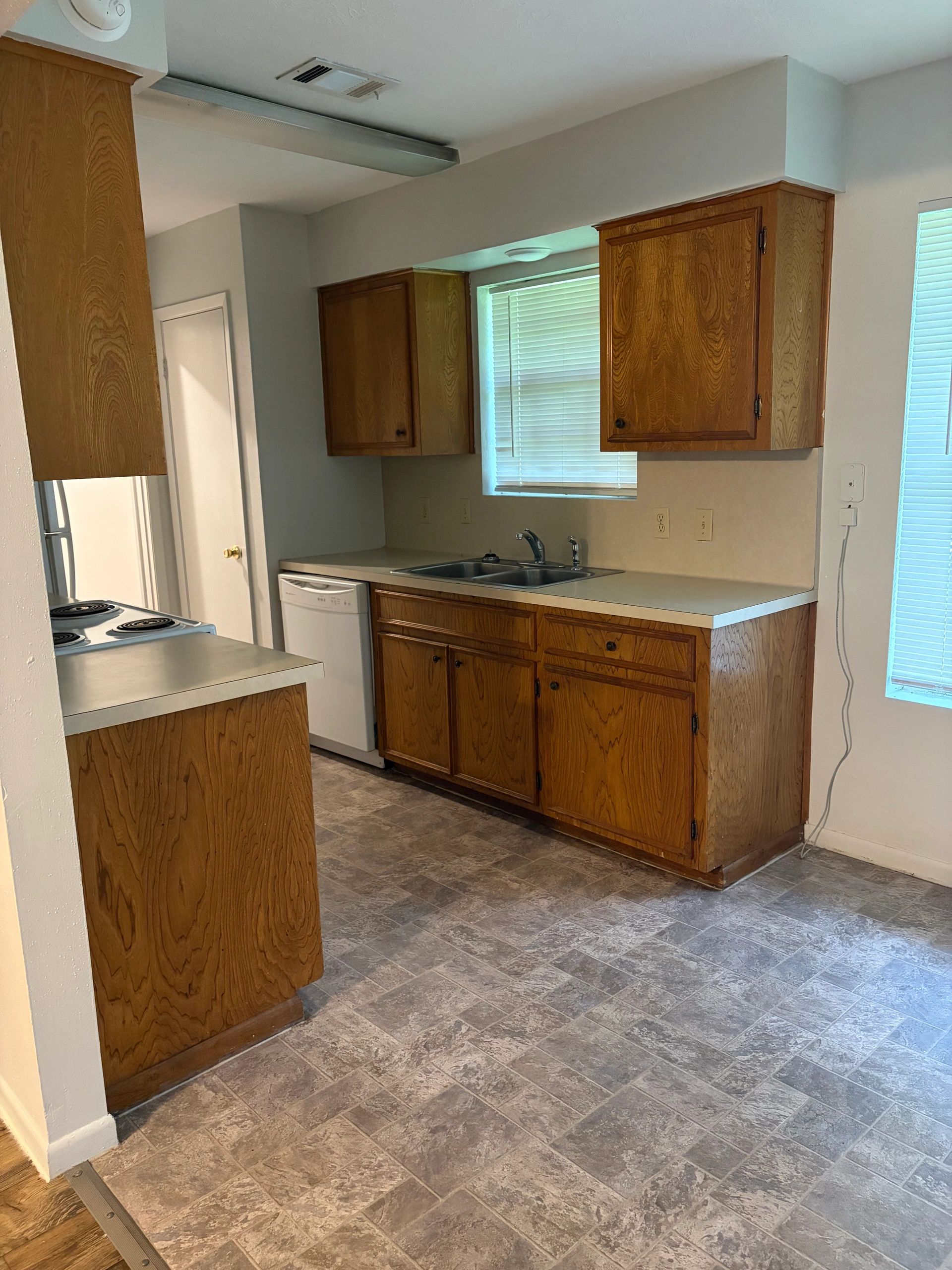 Clean kitchen with wood cabinets and tiled floor.