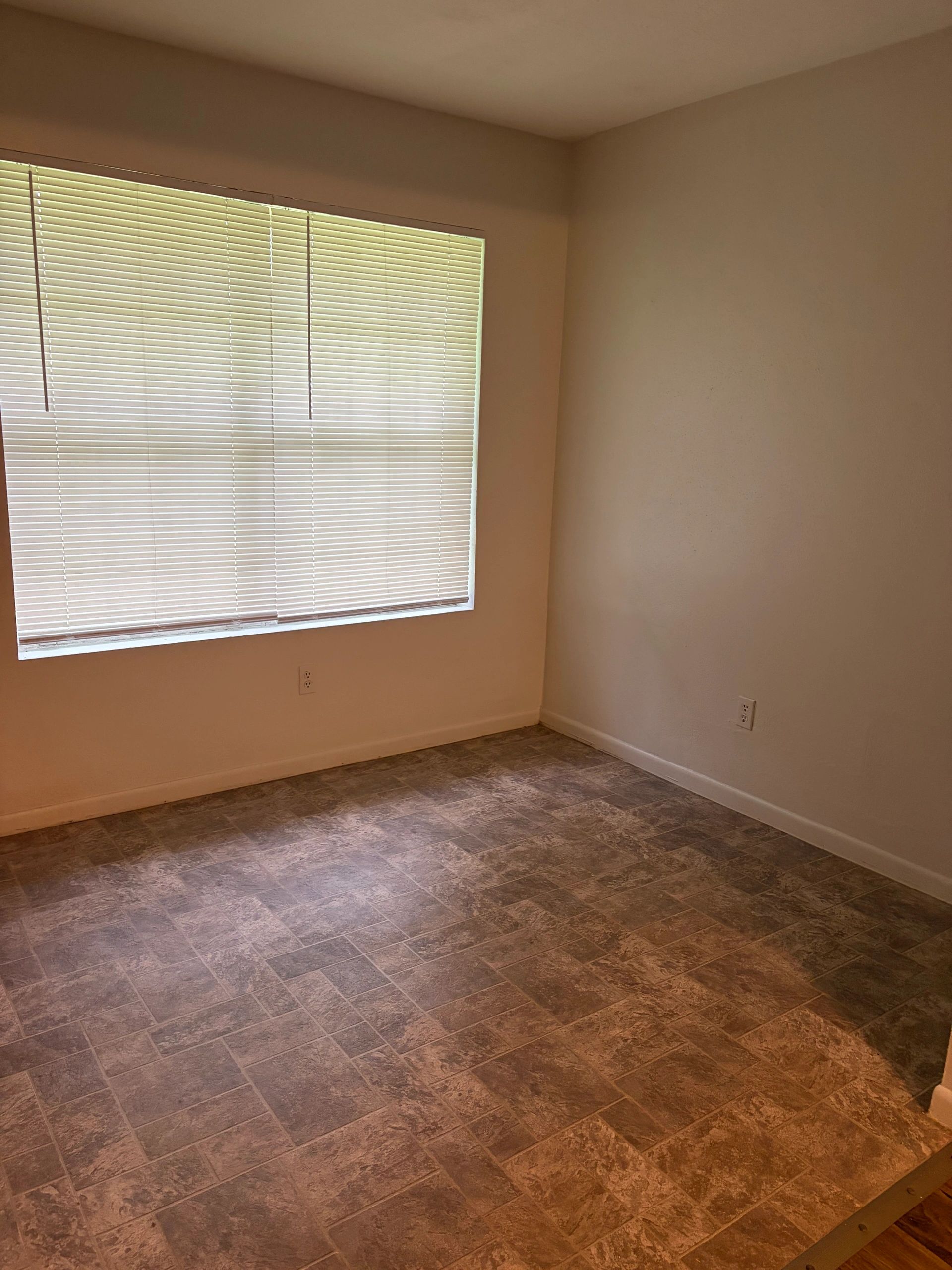 Empty room with tiled floor and window blinds.
