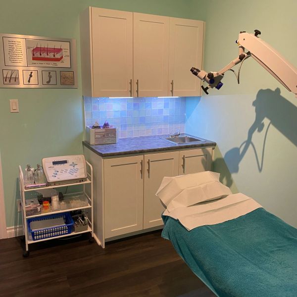 Clean, organized medical or beauty treatment room with examination bed and equipment.