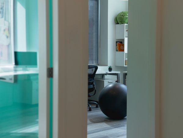 View through a door into a modern office with a black exercise ball.