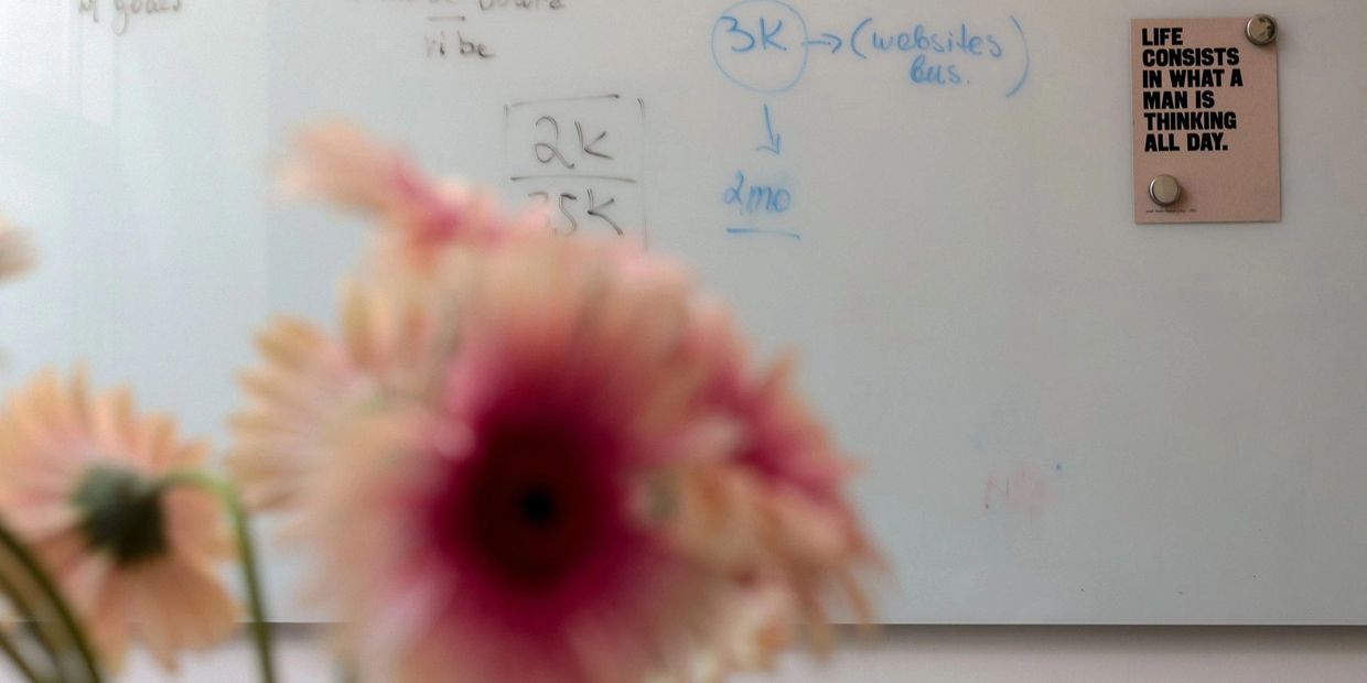 Blurry flowers in front of a whiteboard with a motivational quote.