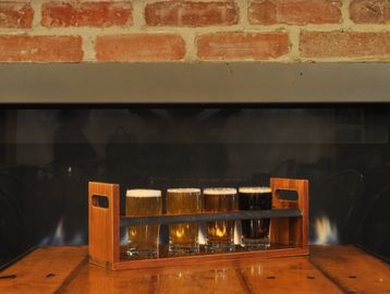 An image of a taster flight sitting in front of the fireplace in the taproom at EBC.