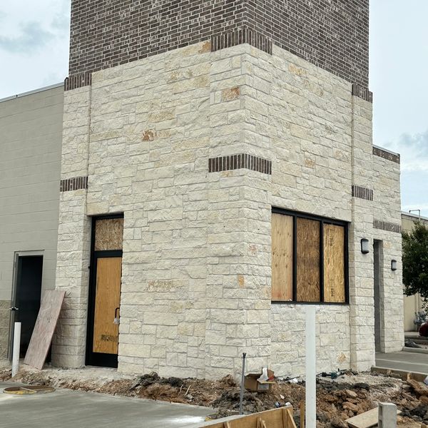 A small building under construction with boarded windows and stone exterior.