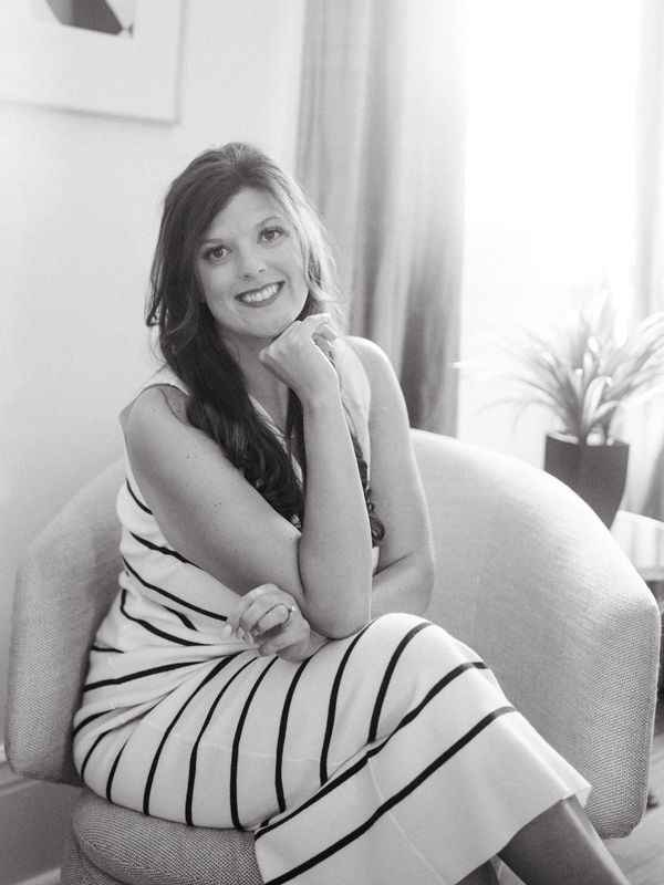 Woman in a striped dress smiling while seated in a modern chair.