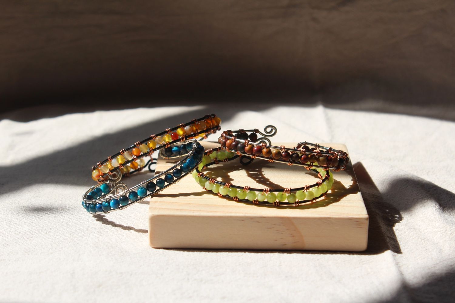 Colorful beaded bracelets displayed on a wooden block with soft natural light.