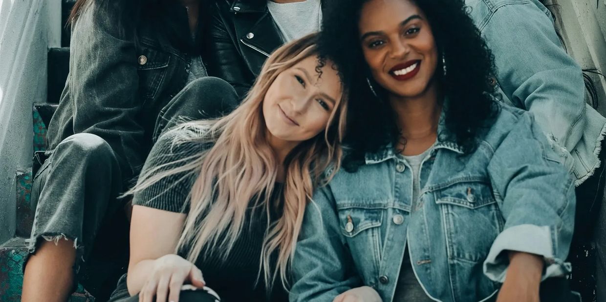 A group of ethnically diverse women sitting on the stairs supporting each other.