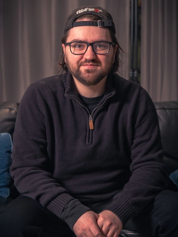 Man wearing glasses and a cap sitting indoors.