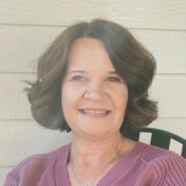 Woman smiling at the camera, wearing a purple top.