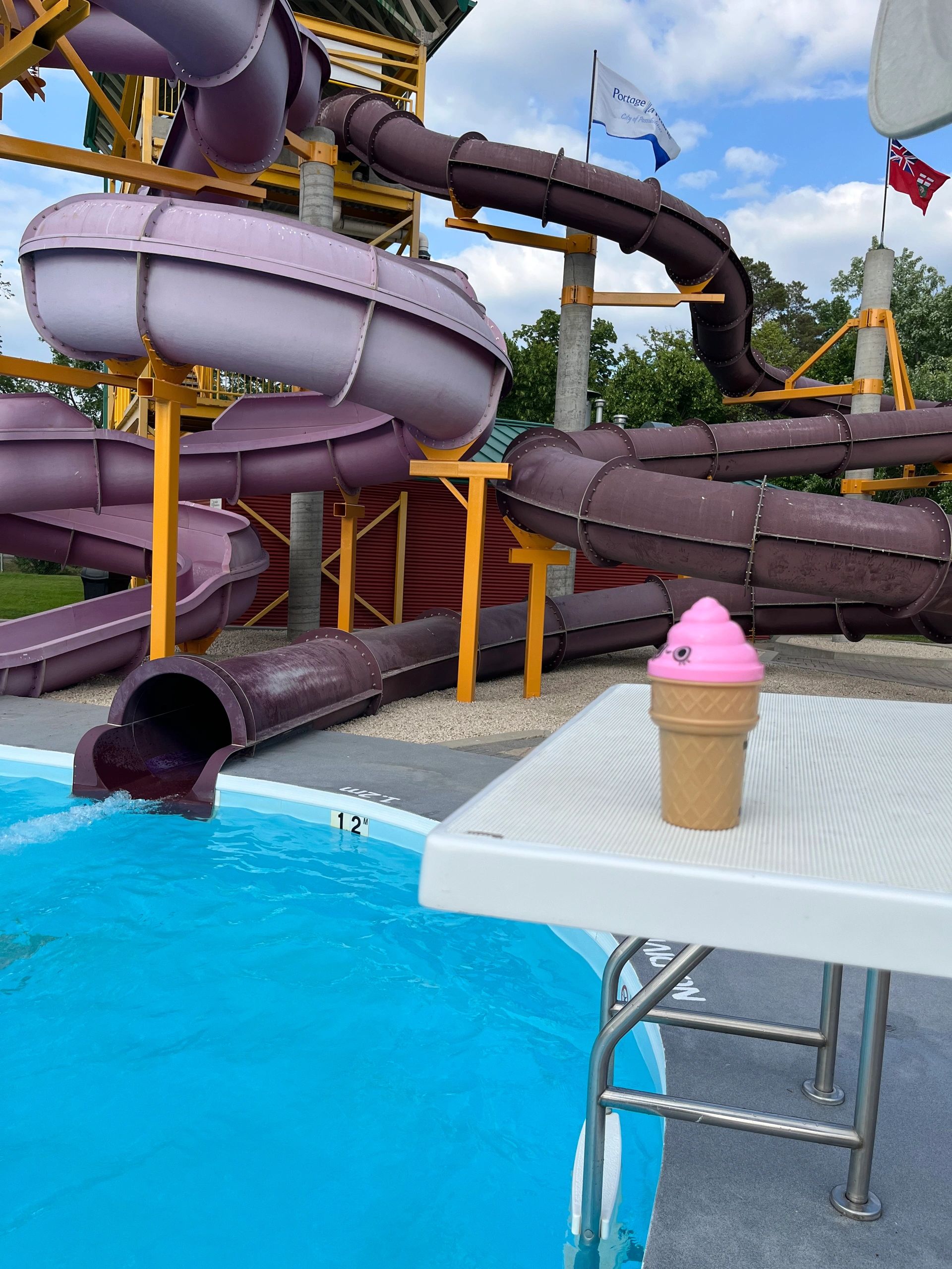Colorful water slides at a pool with a toy ice cream cone in the foreground.