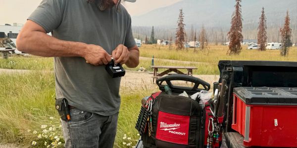 A man working with tools near a truck and a field.