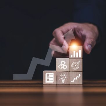 Hand stacking blocks with business growth icons and an upward arrow.