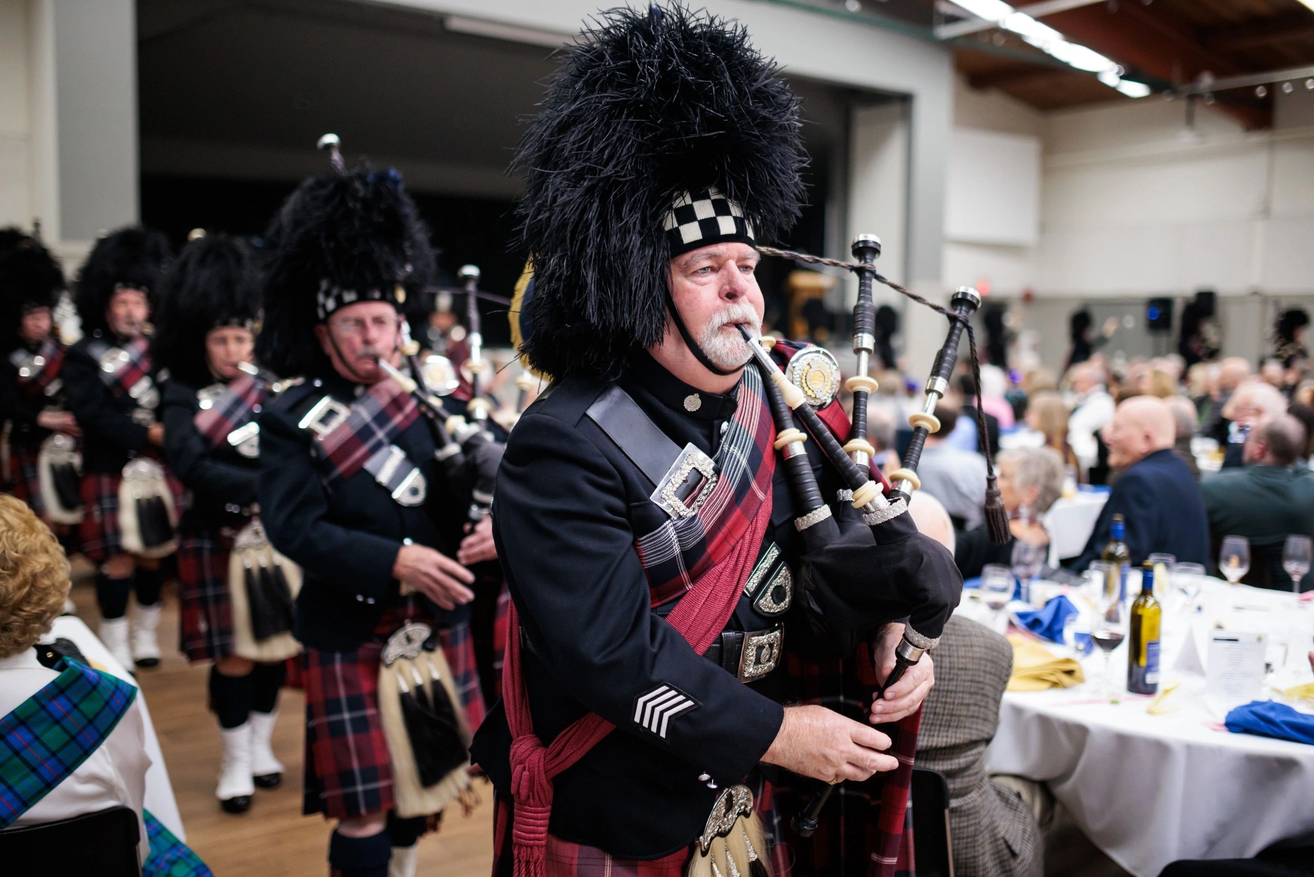 Bagpipers in pipe band marching through room during performance.