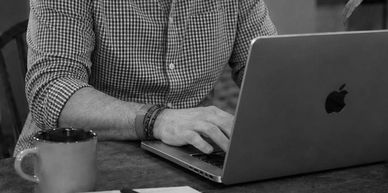 Person typing on a laptop with a coffee mug nearby.