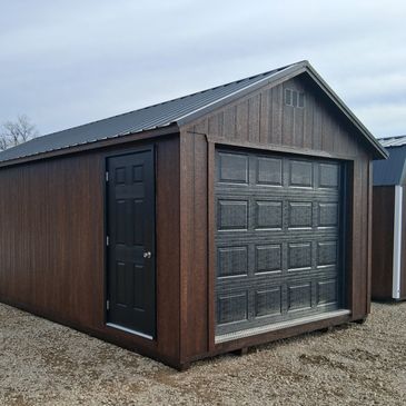 Wooden garage with a black door and garage door on gravel.