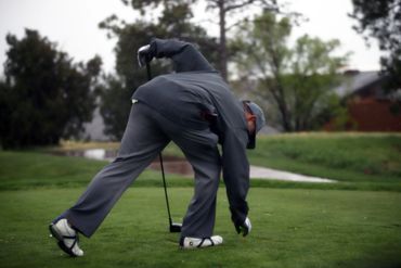 Golfer placing a golf ball on the tee on a green course.