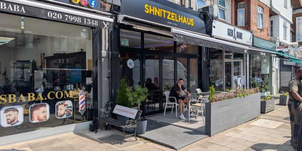 Street view of shops including a barbershop and a restaurant.