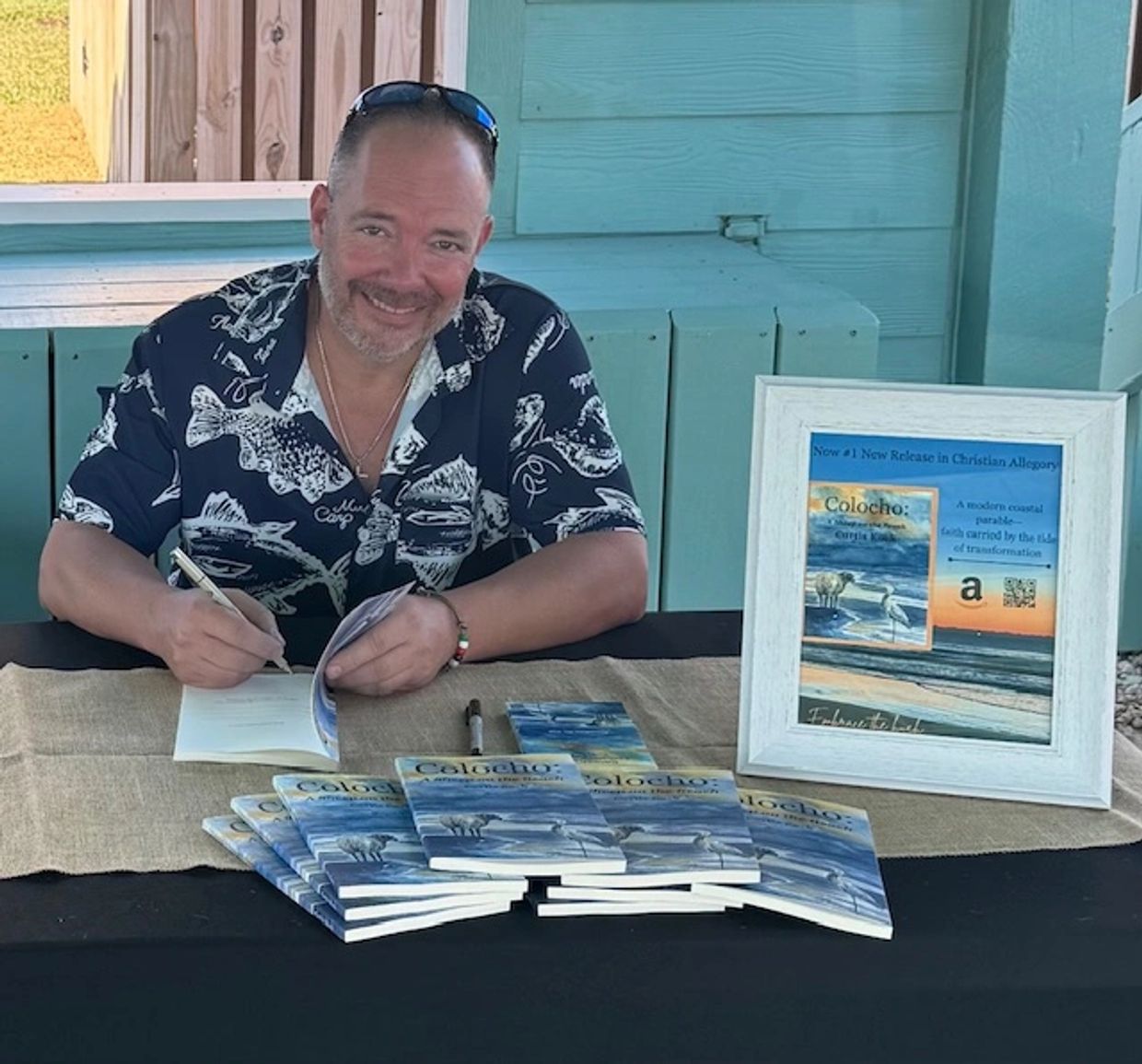 Author signing copies of "Colocho," a modern coastal parable.
