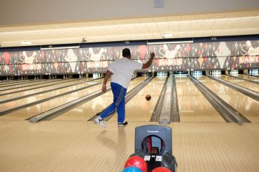 Man bowling a ball down the lane.