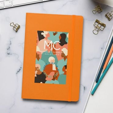 Orange Journal book on desk with white keyboard cup of coffee and pencils