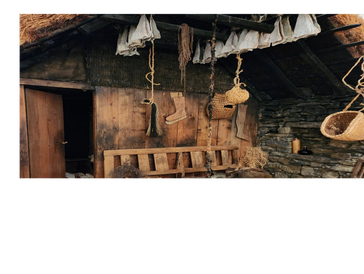 Rustic wooden cabin with hanging baskets and fabrics.