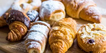 Assorted freshly baked croissants and pastries on a wooden board.