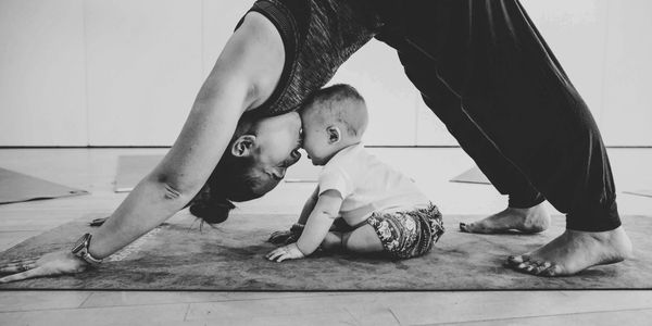 Mum practicing yoga move over her baby during a mum and baby yoga class in Peterborough