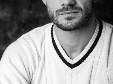 Hombre con barba en suéter blanco de cuello en V.