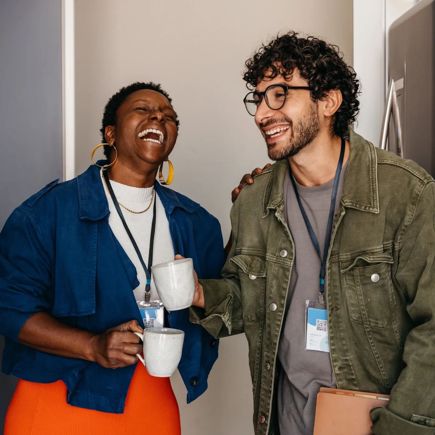 2 people laughing while holding a cup 