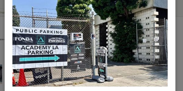 Public parking signs for Academy LA near Fonda Theatre and Pantages are displayed on a fence.