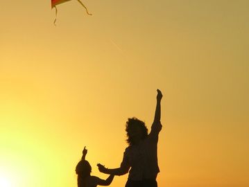 Two people flying a kite at sunset with a golden sky.