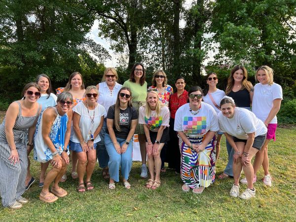 Group of women smiling outdoors in a park setting.