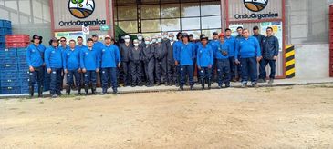Group of workers standing outside a warehouse with Onda Organica signs.