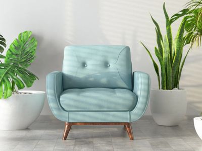 A light blue armchair between two large potted plants in a bright room.